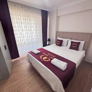 Una habitación de hotel con una cama, una mesita de noche, una lámpara y una ventana con cortinas.