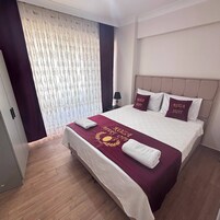 A hotel room with a bed, a nightstand, a lamp, and a window with curtains.
