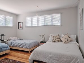 A bedroom with two beds, a nightstand, a lamp, and a framed picture on the wall. - Mid-Century Modern Oasis Near Stanley Marketplace (Aurora)