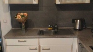 Cozinha com dois armários, uma pia e uma chaleira.