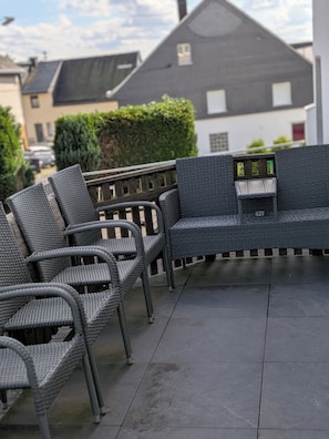 An outdoor patio with wicker furniture, including chairs and a table with a built-in bench. - 🍋 Casa Limone – Your cozy retreat in the Westerwald (not Upland) (Willingen)