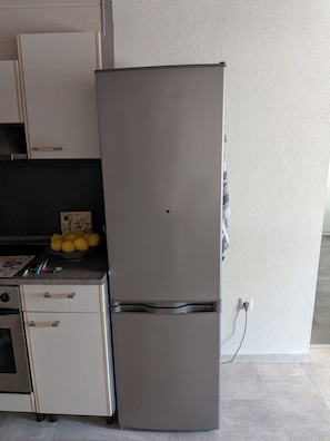 A kitchen with a refrigerator, a stove, and a countertop with lemons and kitchen utensils.
