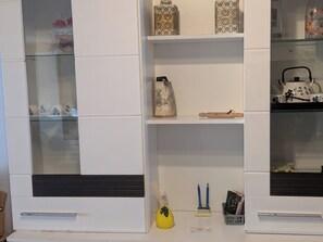 A white cabinet with glass doors containing decorative items and a shelf with a vase, a rolling pin, and writing utensils. - 🍋 Casa Limone – Your cozy retreat in the Westerwald (not Upland) (Willingen)