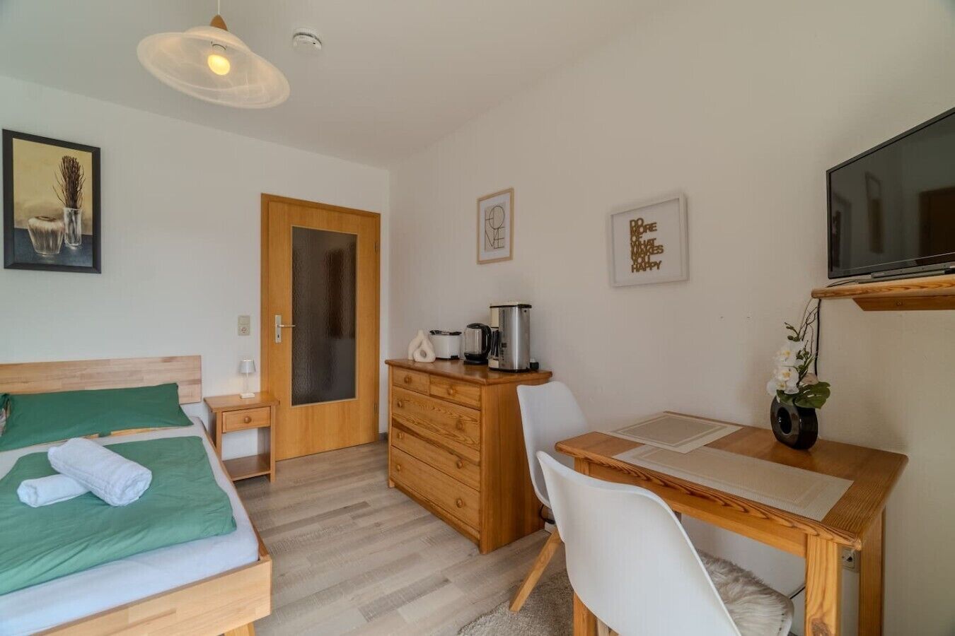 Une chambre d’hôtel avec un lit, un bureau, une chaise, une télévision et une porte.
