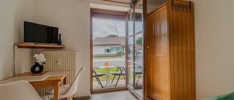 Una habitación con cama, un escritorio con silla, televisión y vistas al exterior.