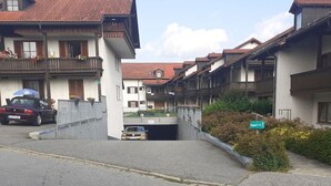 A residential street with houses, a car, and a sign indicating a location. - Cozy 1-room apartment, sauna, swimming pool, parking (Zwiesel)
