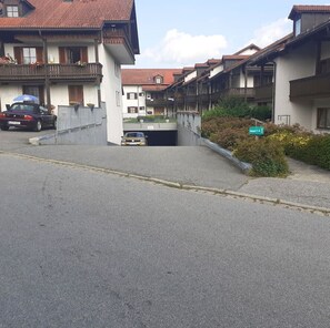 Rua residencial com casas, um carro e uma placa indicando um local.