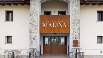 A building with a stone facade and a sign that reads 'VINE DEL MALINA'.