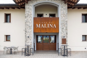 A building with a stone facade and a sign that reads 'VINE DEL MALINA'.