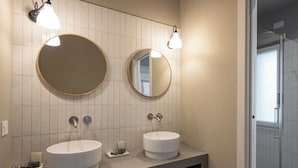 A bathroom with two sinks, a mirror, and a shower.