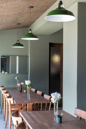 A dining area with a long wooden table, multiple chairs, and two green pendant lights.