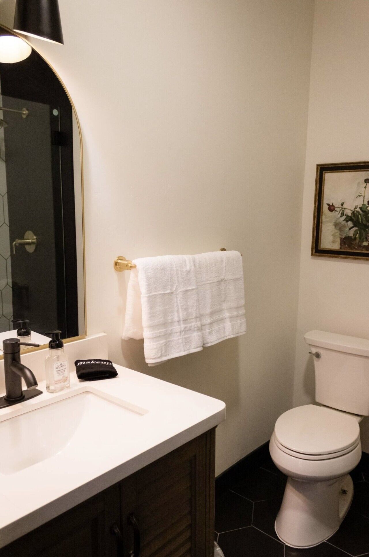 A bathroom with a white sink, black faucet, and a white toilet.
