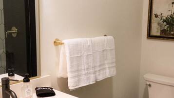 A bathroom with a white sink, black faucet, and a white toilet.