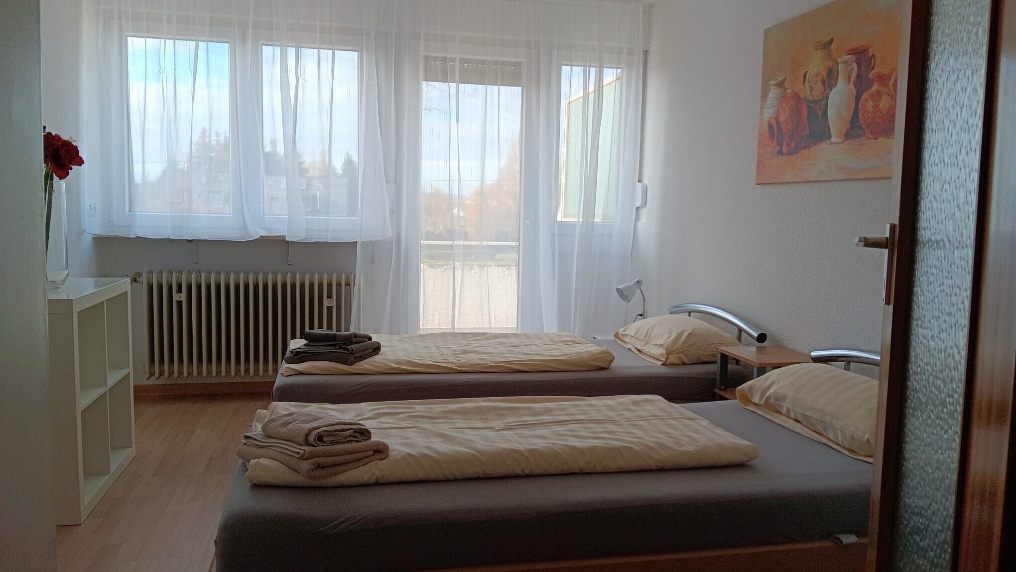 Une chambre avec deux lits, un radiateur, un bureau et un tableau accroché au mur.