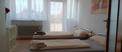 Una habitación con dos camas, un radiador, un escritorio y un cuadro en la pared.