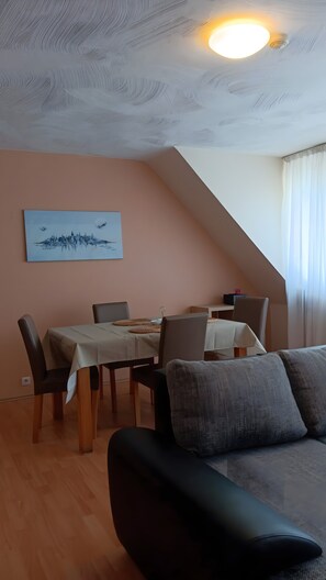 A dining area with a table and chairs, a sofa, and a ceiling light. - Apartment 'Haus Abendsonne Top Floor' with Terrace, Garden & Wi-Fi (Koblenz)