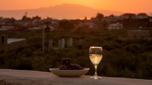 A sunset with a bowl of grapes and a glass of white wine on a ledge. - Kamak Villa I (West Mani)