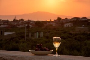 A sunset with a bowl of grapes and a glass of white wine on a ledge. - Kamak Villa I (West Mani)