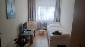 A small, tidy room with a bed, a desk with a computer, a chair, and a window with curtains. - Apartment 'Haus Abendsonne Großes Hochparterre' with Private Terrace, Shared Garden and Wi-Fi (Koblenz)