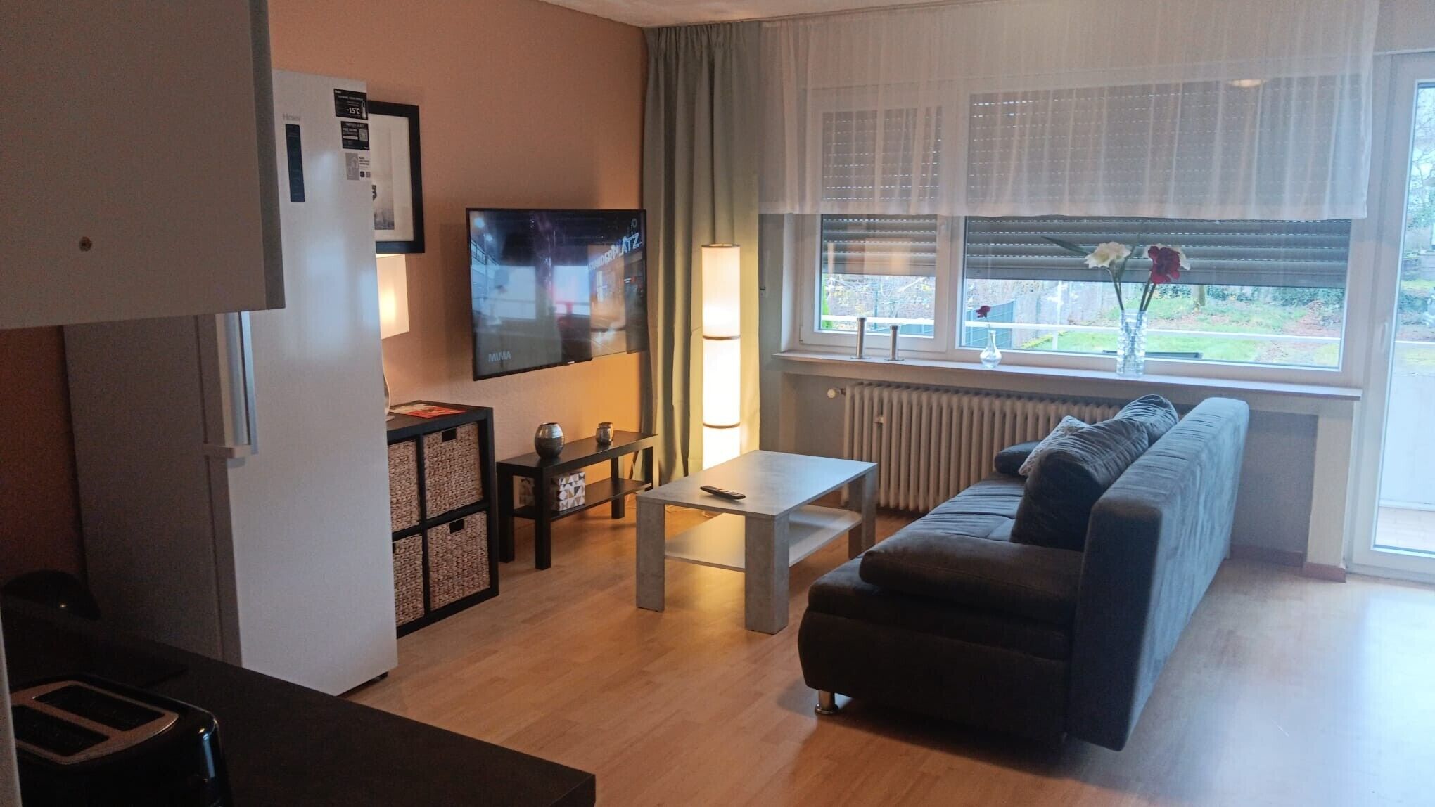 Un salon moderne avec un canapé, une table basse, un téléviseur et une fenêtre donnant sur un beau paysage.