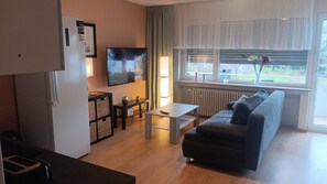 A modern living room with a sofa, a coffee table, a TV, and a window with a view. - Apartment 'Haus Abendsonne Großes Hochparterre' with Private Terrace, Shared Garden and Wi-Fi (Koblenz)