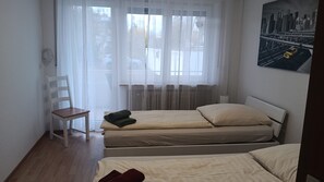 A room with two beds, a chair, and a window with sheer curtains. - Apartment 'Haus Abendsonne Großes Hochparterre' with Private Terrace, Shared Garden and Wi-Fi (Koblenz)