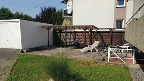 Terassi, jossa on puinen pergola, nurmikko ja pyöräteline.