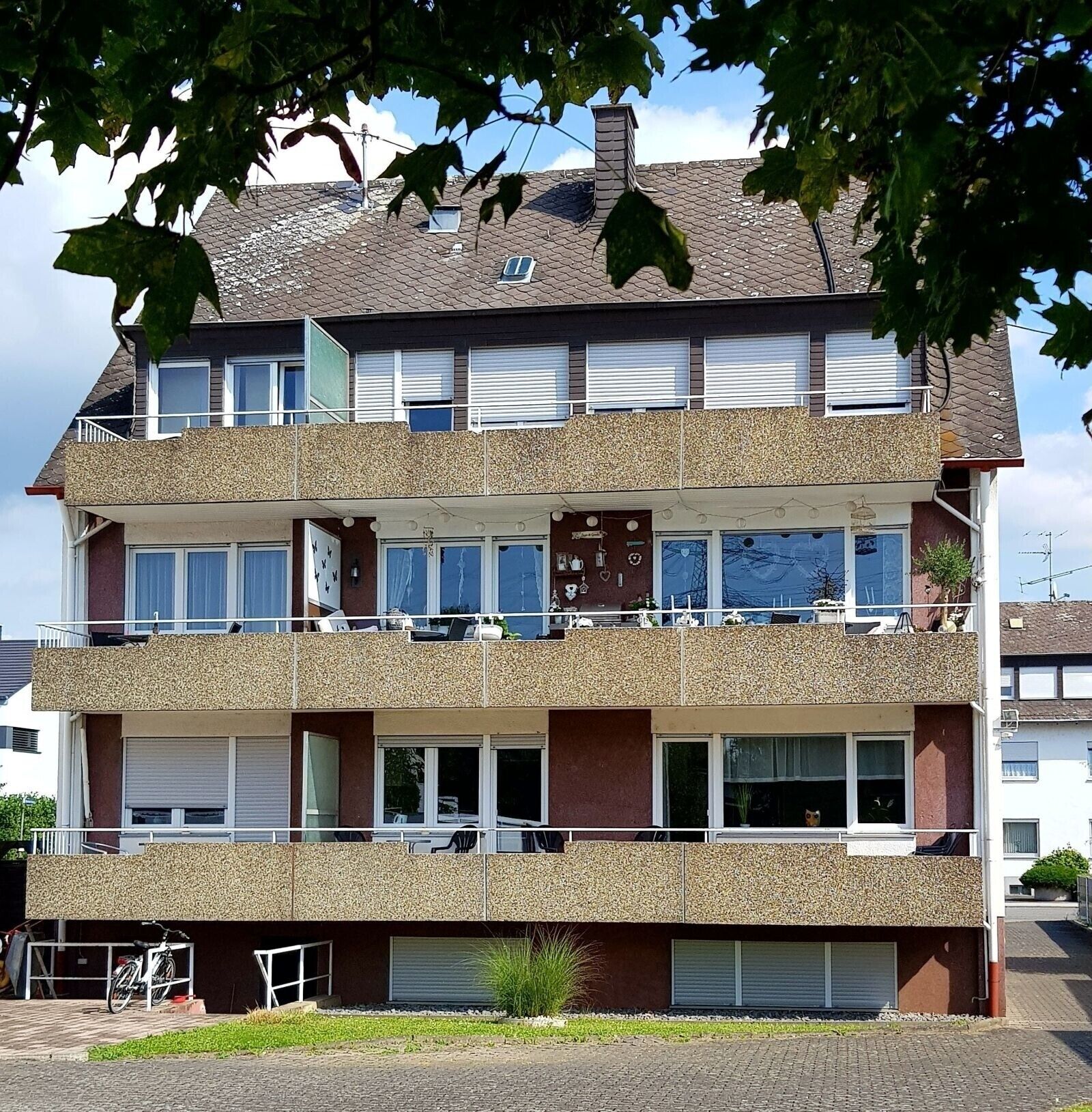 Ein mehrstöckiges Wohngebäude mit Balkonen, Fenstern und einer Garage.