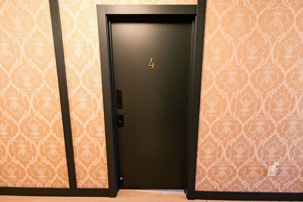 A door with a number '4' on it, set in a hallway with patterned wallpaper.