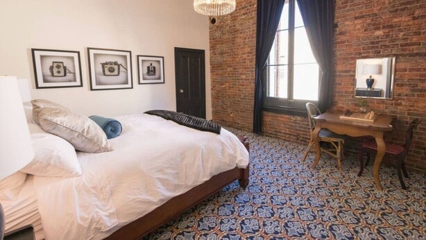 A bedroom with a large bed, a desk, and a chandelier.