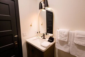 A bathroom with a white sink, a mirror, a black towel, and a black makeup bag.