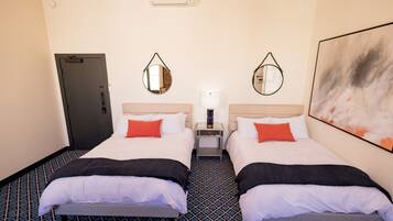 A hotel room with two beds, a nightstand, a mirror, and a painting on the wall.