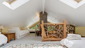 A bedroom with a sloped ceiling, two skylights, a bed, a chair, and a wooden decorative structure. - Lake, Mountain & Fall Colors-Your Hallmark-Moment (Cullowhee)