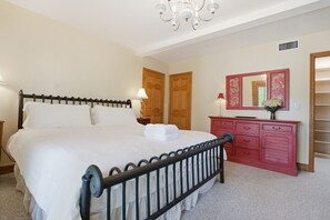 A bedroom with a bed, a dresser, a mirror, and a door.