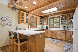 A kitchen with wooden cabinets, a central island, and a dining area with chairs.