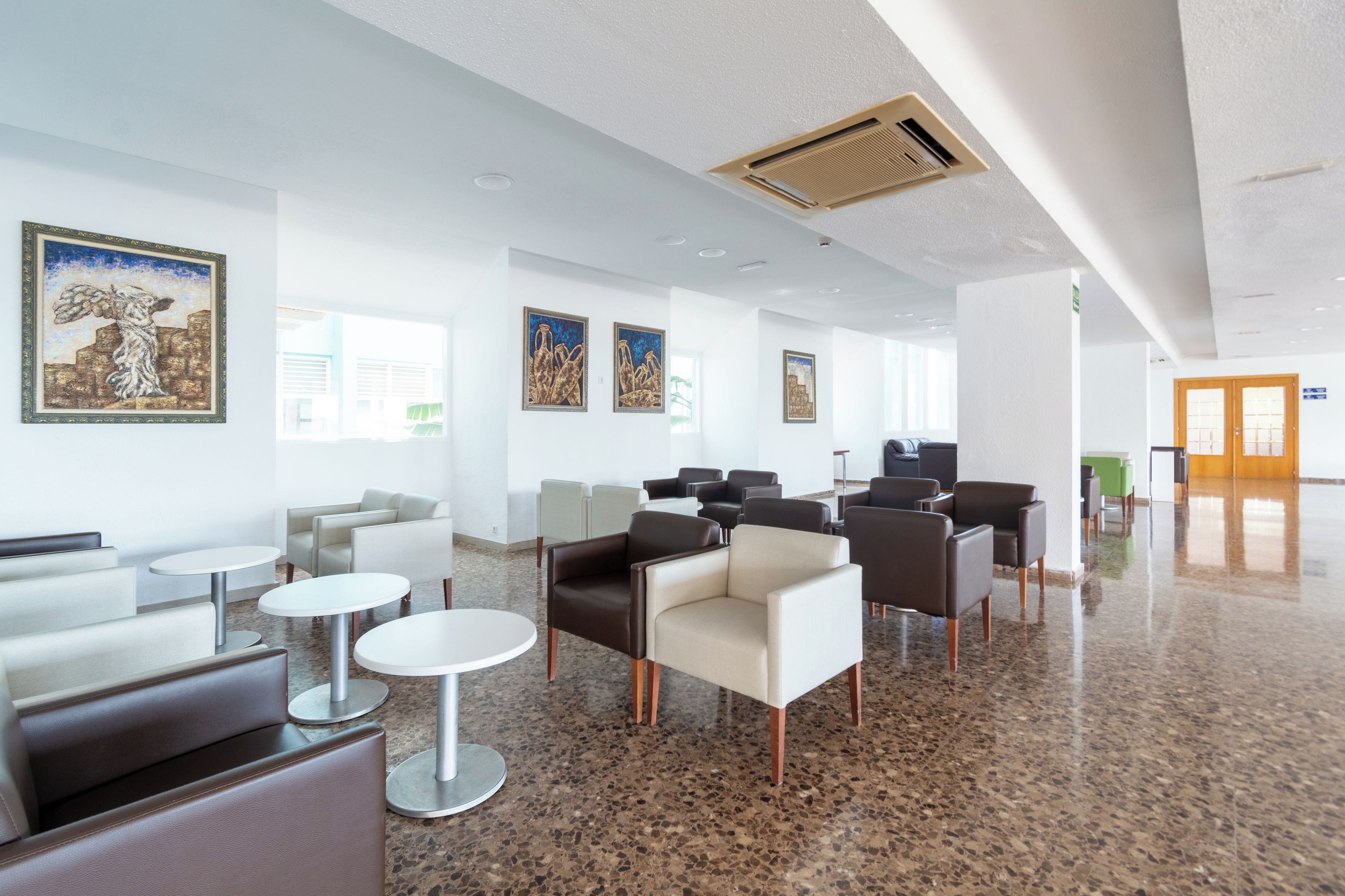 A modern lobby with seating areas, artwork on the walls, and a polished floor.
