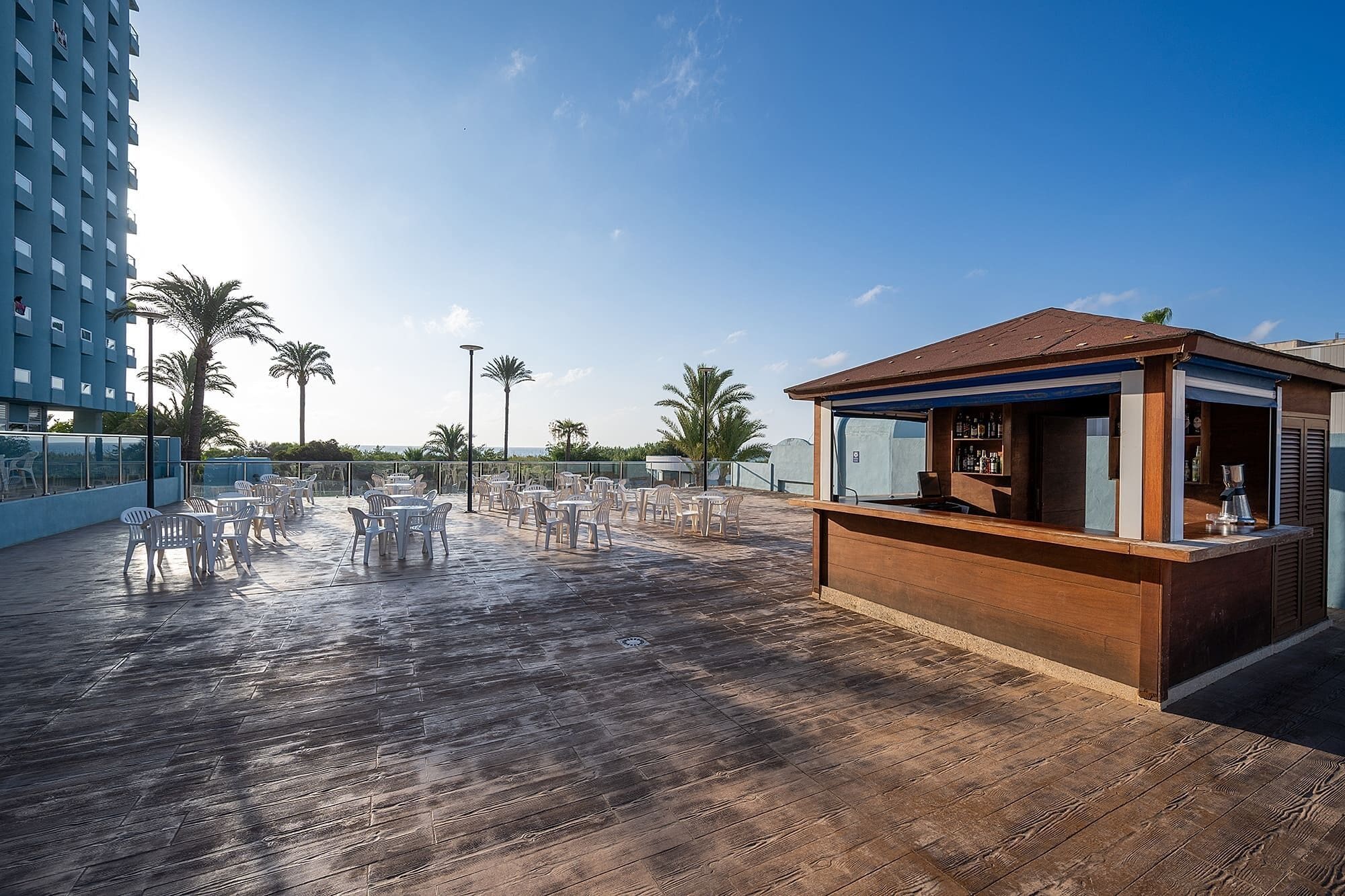 A rooftop bar with outdoor seating and a view of the ocean.