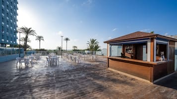 A rooftop bar with outdoor seating and a view of the ocean.