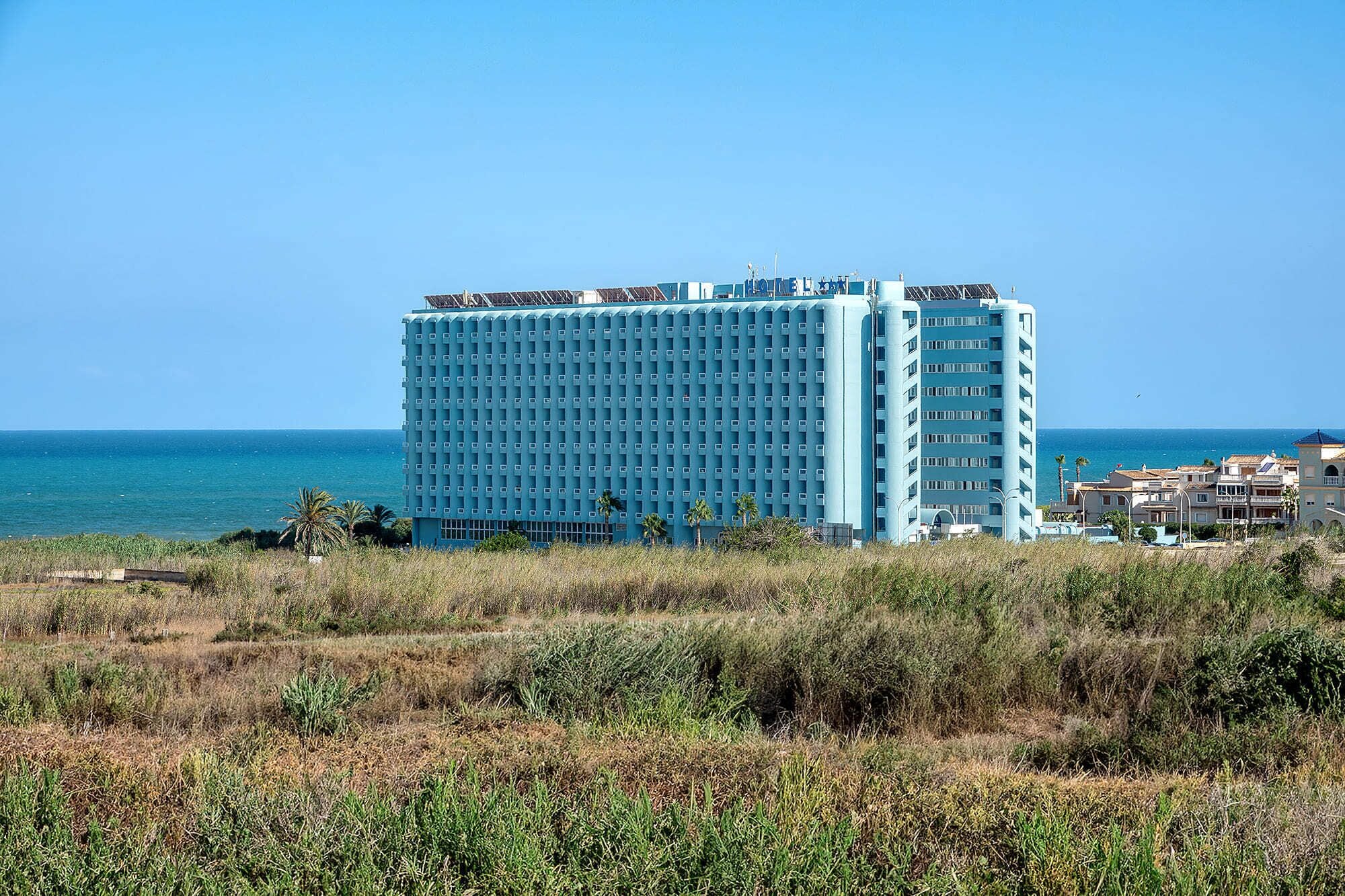 Un grand hôtel, avec une façade uniforme, situé près d’une côte.