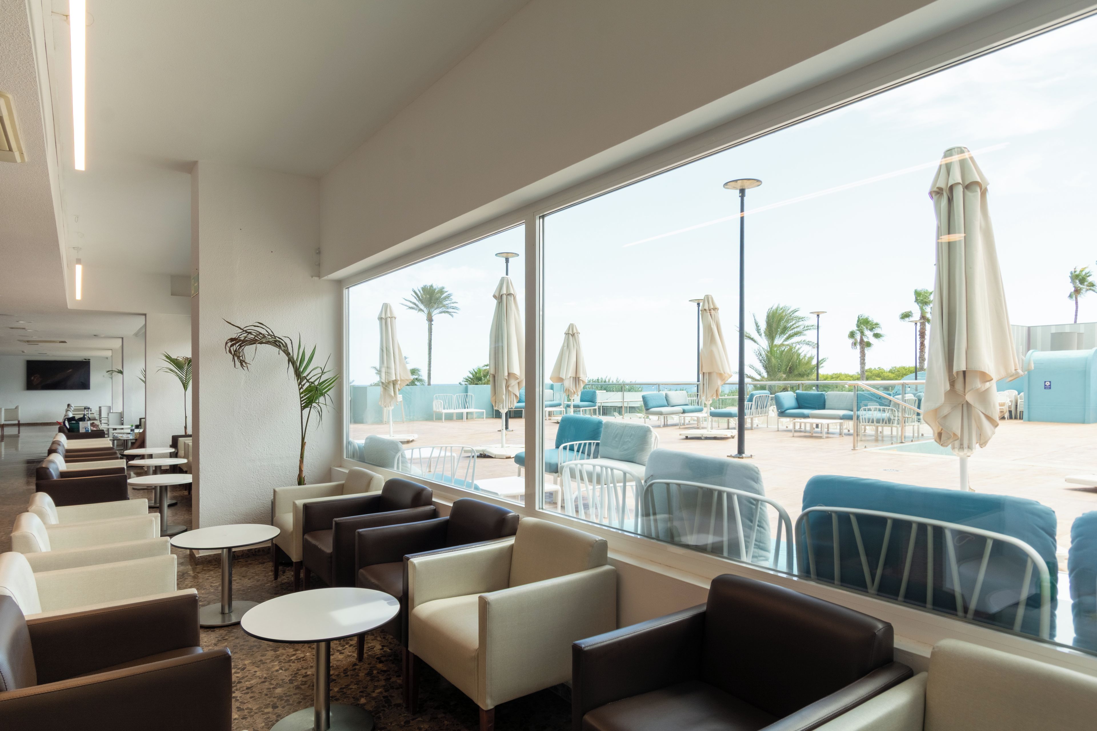 Vestíbulo de hotel con asientos, una recepción y vistas al área de la piscina.