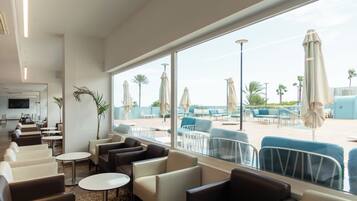 Vestíbulo de hotel con asientos, una recepción y vistas al área de la piscina.