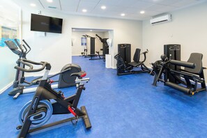 Un gimnasio con equipo de ejercicio variado, incluyendo cintas de correr, máquinas de pesas y una bicicleta estática.