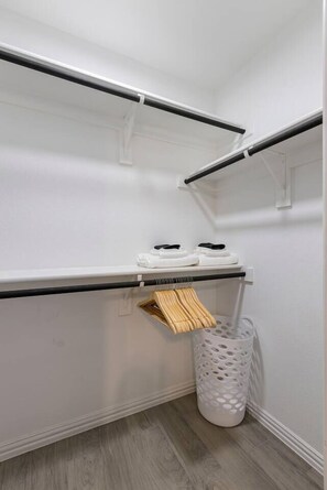 Ein Schrank mit Kleiderstange, Ablagefläche und Mülleimer.