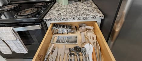 Una cocina con estufa de acero inoxidable, un organizador de cajones con utensilios y una especiero.