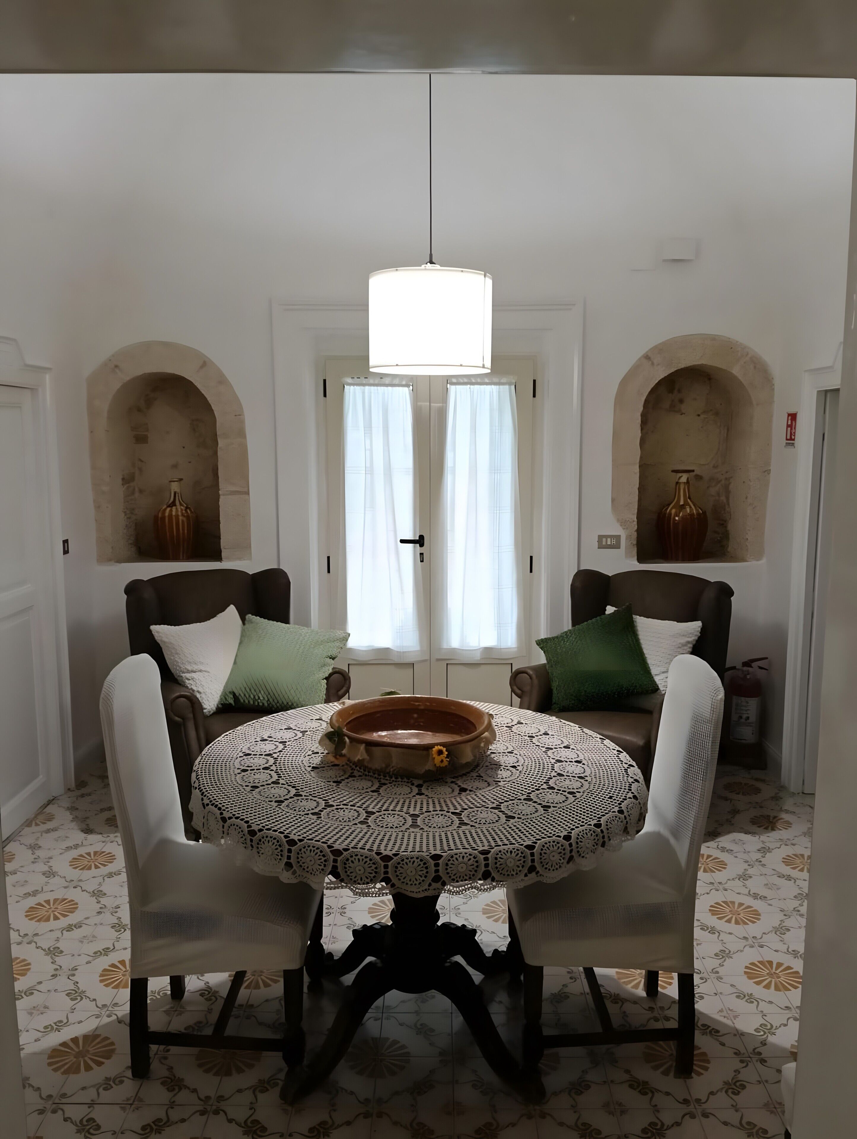 A dining area with a round table, chairs, and a central light fixture.