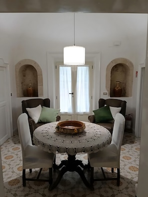 A dining area with a round table, chairs, and a central light fixture.