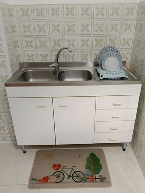 A kitchen with a double sink, a dish rack, and a patterned backsplash.