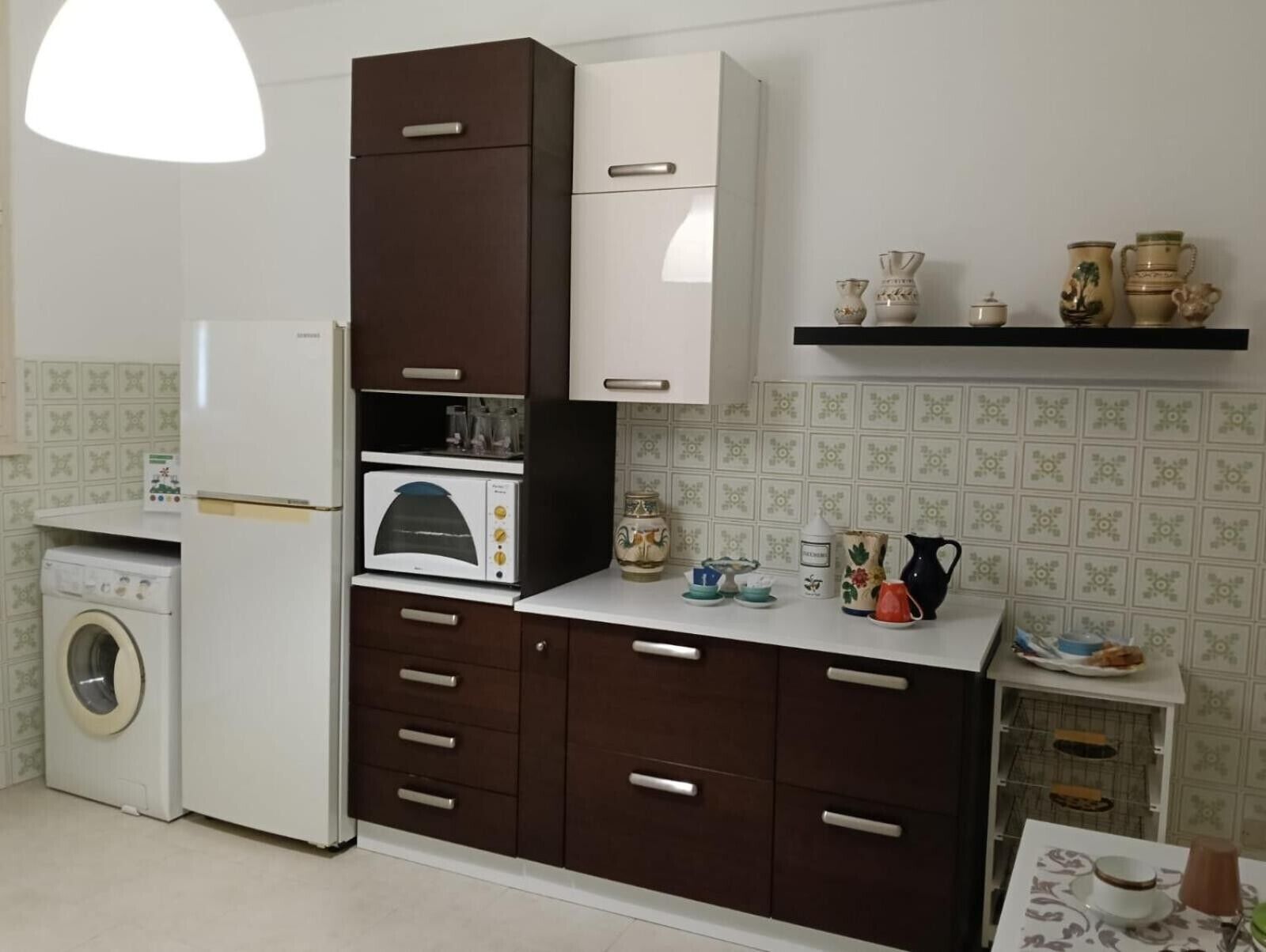 Una cucina compatta con lavatrice, forno a microonde e piccolo forno.