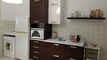 Una cucina compatta con lavatrice, forno a microonde e piccolo forno.