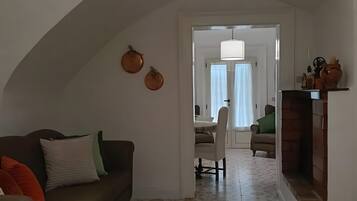 Uma sala de estar com sofá, banquinho e luminária pendente.